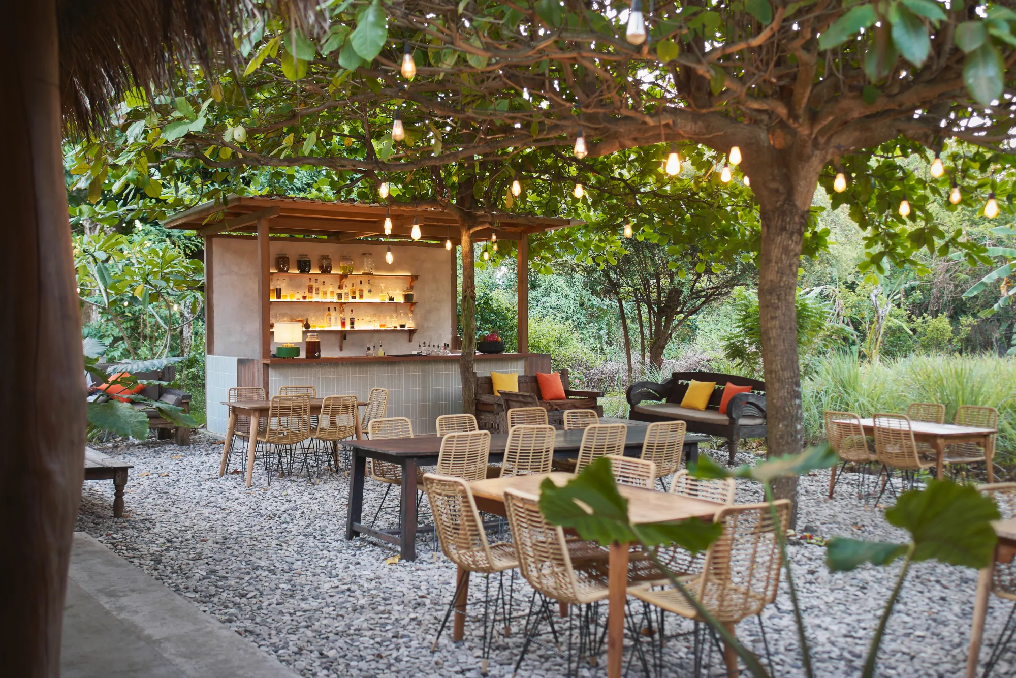 The thatched garden bar at Seed in Bingin by day, seen through frangipani and palms