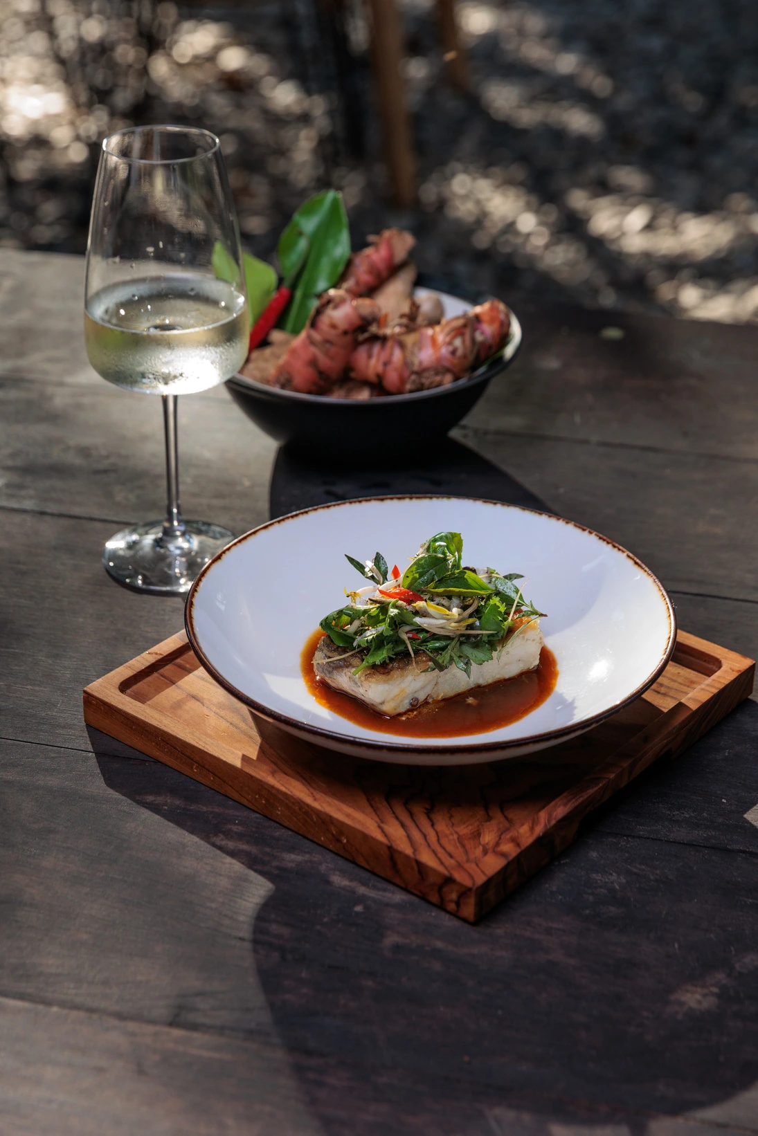 A plated fish main course with a glass of white wine at Seed in Bingin