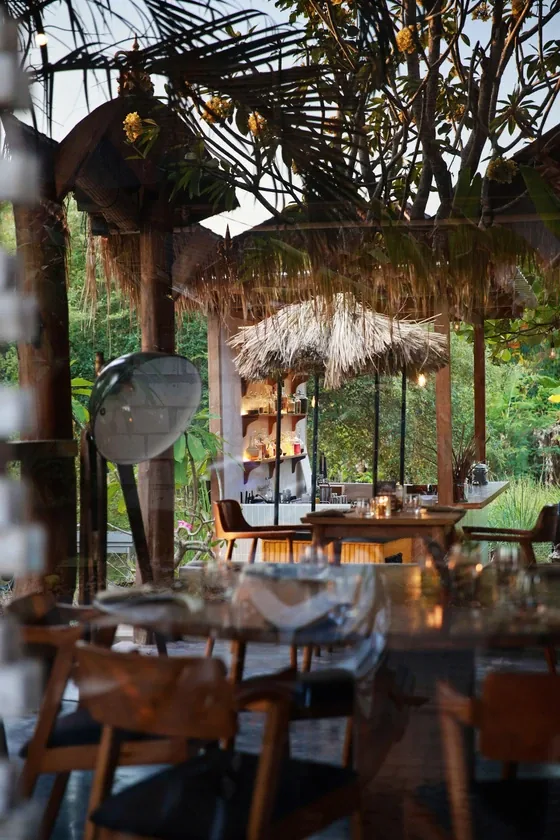 The open air thatched dining room at Seed in Bingin, laid tables looking out onto the garden